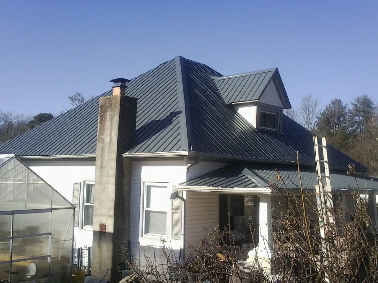 Dark blue standing seam metal roof on a white farmhouse with dormer — Slate & Tile Roof Repair by Roofing Brothers in Dearing