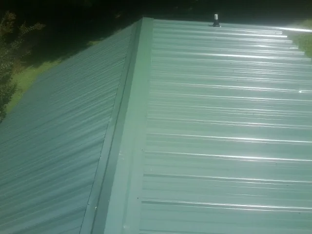 New green metal panels meeting at the ridge of a roof — Flat Roof Repair work by our crew in Dearing